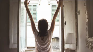 Person stretching by a window in the morning